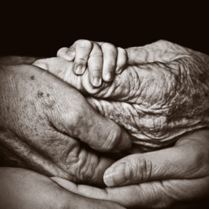 The layered hands of several generations in a family.